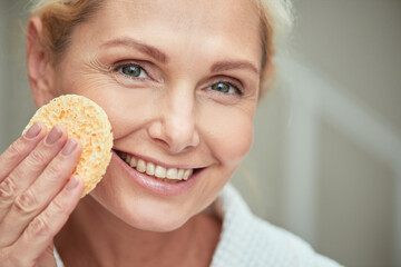 Smiling middle aged caucasian woman with facial sponge