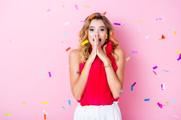 elegant shocked woman in crown under confetti on pink background