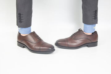 Classic brown men's leather shoes dressed on hands on a white background