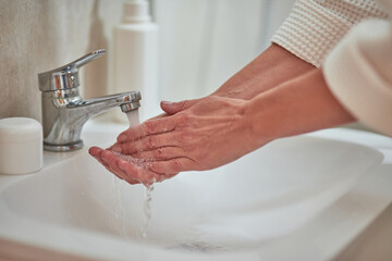 Woman washing hands with water in bathroom