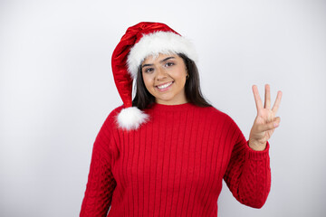 Young beautiful woman wearing a Santa hat over white background showing and pointing up with...