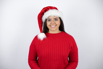 Young beautiful woman wearing a Santa hat over white background with a happy face standing and smiling with a confident smile showing teeth