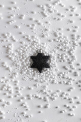 Christmas  black star  in the snow. New Year's decor. Christmas or winter composition. Snowflakes and snowball on a white background.Christmas, winter, new year concept. Flat lay, top view.