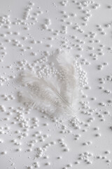 Christmas white feathers  in the snow. New Year's decor. Christmas or winter composition. Snowflakes and snowball on a white background.Christmas, winter, new year concept. Flat lay, top view.