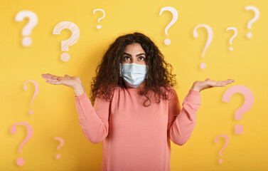 Girl with face mask has a lot of question about covid 19. Yellow background