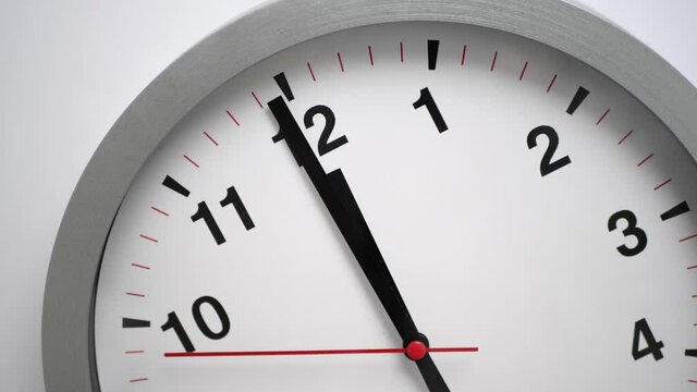 Close up of a white ticking clock on white background, pointing midnight