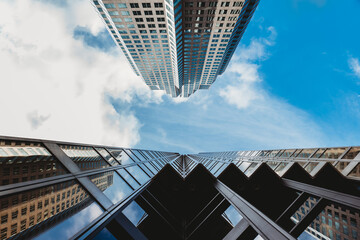 Looking up at the blue sky with skyscrapers and clouds.