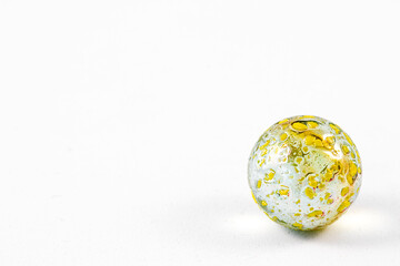 Close up of small yellow speckled glass marble