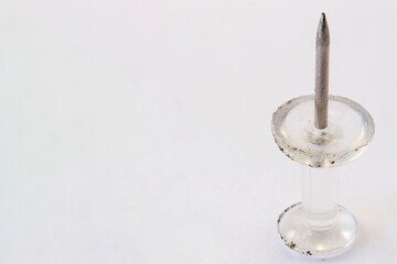 Close up of thumbtack standing up on white