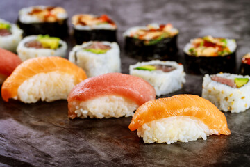 Close up of sushi rolls with red salmon on black background. Japanese food.