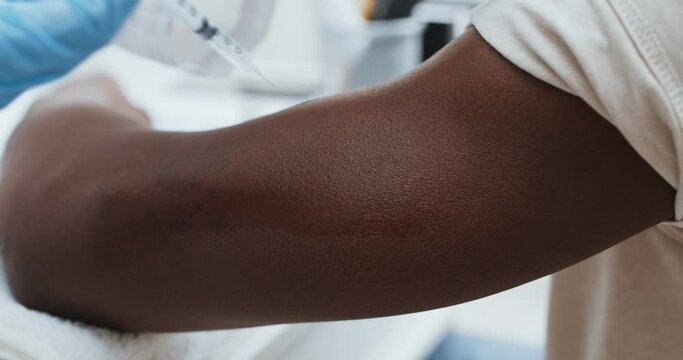 Adult black patient getting vaccine injection in hand at hospital, close up. Immunity stimulation concept