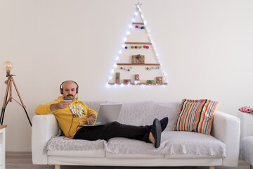 Young man doing shopping by credit card lying down on sofa at his home.
