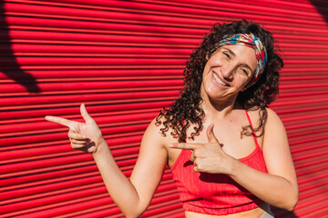 Naklejka premium A young athlete in sportswear pointing her index fingers to the side - Photo of young sportsman positive point index finger isolated empty space on red background .