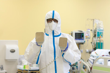 Male nurse with protective coverall clothing in intensive care unit. Nurse is holding...