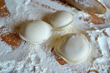 Homemade dumplings on the table in flour. Rolling pin.
