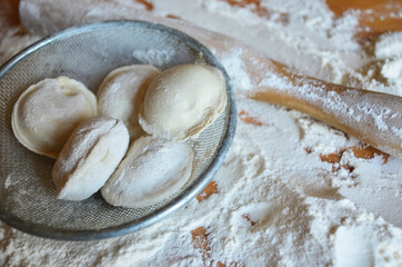 Homemade dumplings on the table in flour. Rolling pin.