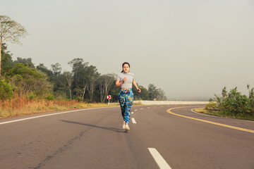 Obraz premium Young sportswoman running in the middle of the road - Female athlete working outdoors.
