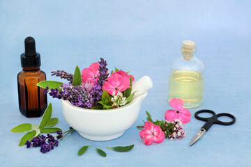 Essential oil preparation for use in aromatherapy & natural herbal medicine with summer flowers, herbs and oil bottles. Naturopathic alternative health care concept.
