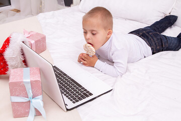 A boy with Down syndrome lies on the couch and licks a lollipop, a child looks at a laptop, video...