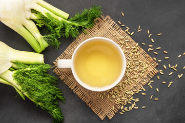 Herbal infusion fennel tea in glass cup or mug with dried fennel seeds and fennel bulbs....