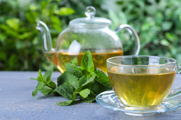 Fresh green tea with mint leaves on light grey wooden table