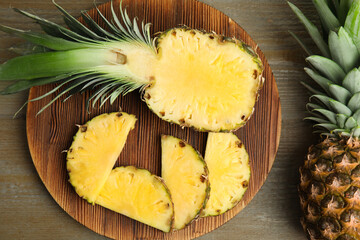 Whole and cut pineapples on wooden table, flat lay