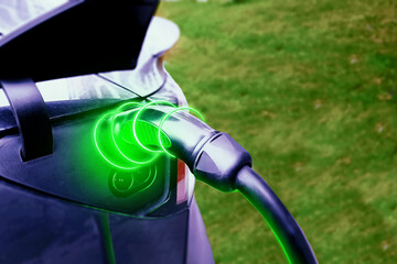 Charging an electric car with the power cable supply plugged in. Develops network of the charging stations across the US and the world. Close up of power supply plugged into an electric car.