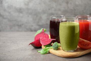 Delicious vegetable juices and fresh ingredients on grey table. Space for text