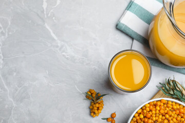 Fototapeta premium Sea buckthorn juice and fresh berries on light marble table, flat lay. Space for text