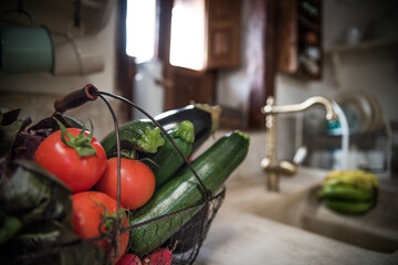 basket of vegetables on top of a kitchen counter and a background wooden window