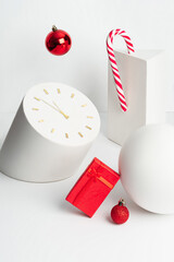 Red Gift box, Candy cane and Christmas balls with white geometric figures on a white background, modern still life