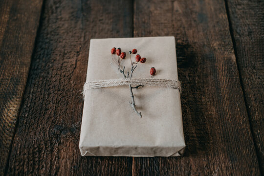 Eco-Friendly, Sustainable, zero waste christmas gift wrapped in kraft paper with twine and berry decor. Christmas wrapped gift box with natural decor on wooden background