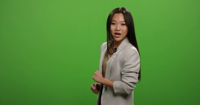 Television news reporter talking during an ad. Female anchor turning around in teaser of evening news program, shot on green chroma key background 4k footage