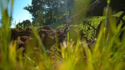 LOW ANGLE: Gardener tips over a wheelbarrow and scatters soil across the lawn.