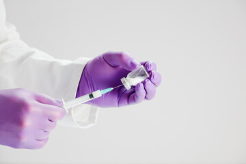 doctor with vaccine and syringe in hands, lilac surgical gloves, white background