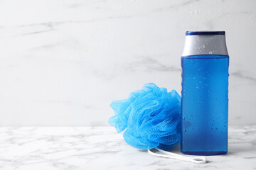 Bottle with water drops and bast wisp on white marble table, space for text. Men's cosmetics