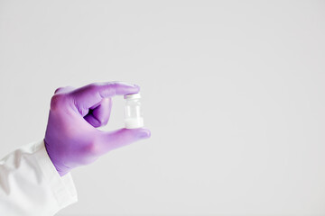 Vaccine in hand of doctor with surgical gloves, white background.