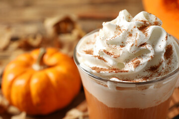 Delicious pumpkin latte with whipped cream on table, closeup
