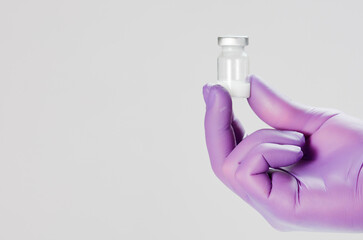 Vaccine in hand of doctor with surgical gloves, white background.