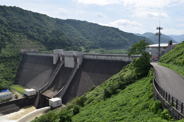Fototapeta premium 月山ダム（がっさんダム）／ 山形県鶴岡市の一級河川、赤川水系の梵字川に建設されたダムです。高さ123メートルの重力式コンクリートダムで、洪水調節、不特定利水、上水道、発電を目的とする、国土交通省直轄の多目的ダムです。ダム湖（人造湖）は、あさひ月山湖（あさひがっさんこ）と言います。
