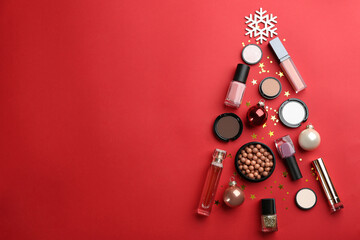 Christmas tree shape of decorative cosmetic products on red background, flat lay with space for text. Winter care