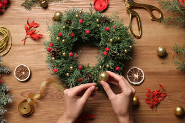 Florist making beautiful Christmas wreath at wooden table, top view © New Africa