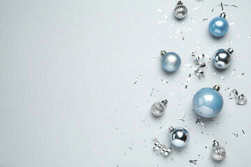 Flat lay composition with shiny Christmas balls, confetti and streamers on light background, space...