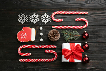 Flat lay composition with candy canes and Christmas decor on black wooden table