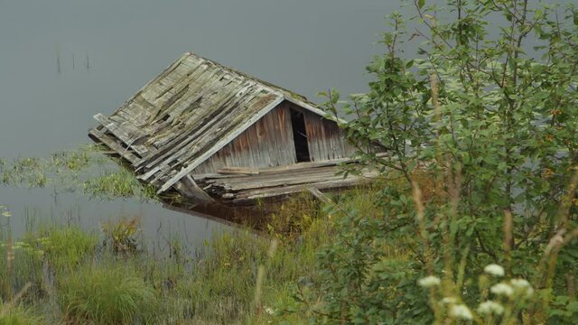 The old rickety wooden house in the water on the shore of a lake in Karelia, Russia.