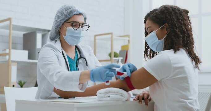 Female lab assistant applying tourniquet on patient arm before taking venous blood for test or intravenous injection