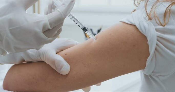 Close up shot of doctor injecting vaccine to female hand, flu and coronavirus prevention
