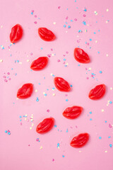 Red fruit chewing marmalade in the shape of a lips on a pink background. Flat lay, top view.