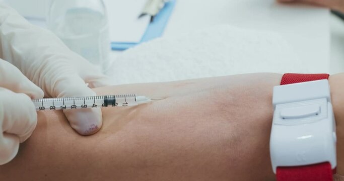 Close up shot of doctor injecting syringe into patient vein and inputing medicine, close up