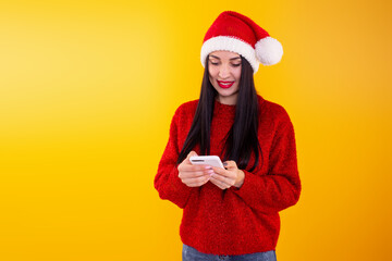 Young beautiful girl in a red Santa hat holds a phone in his hands. Christmas discount content